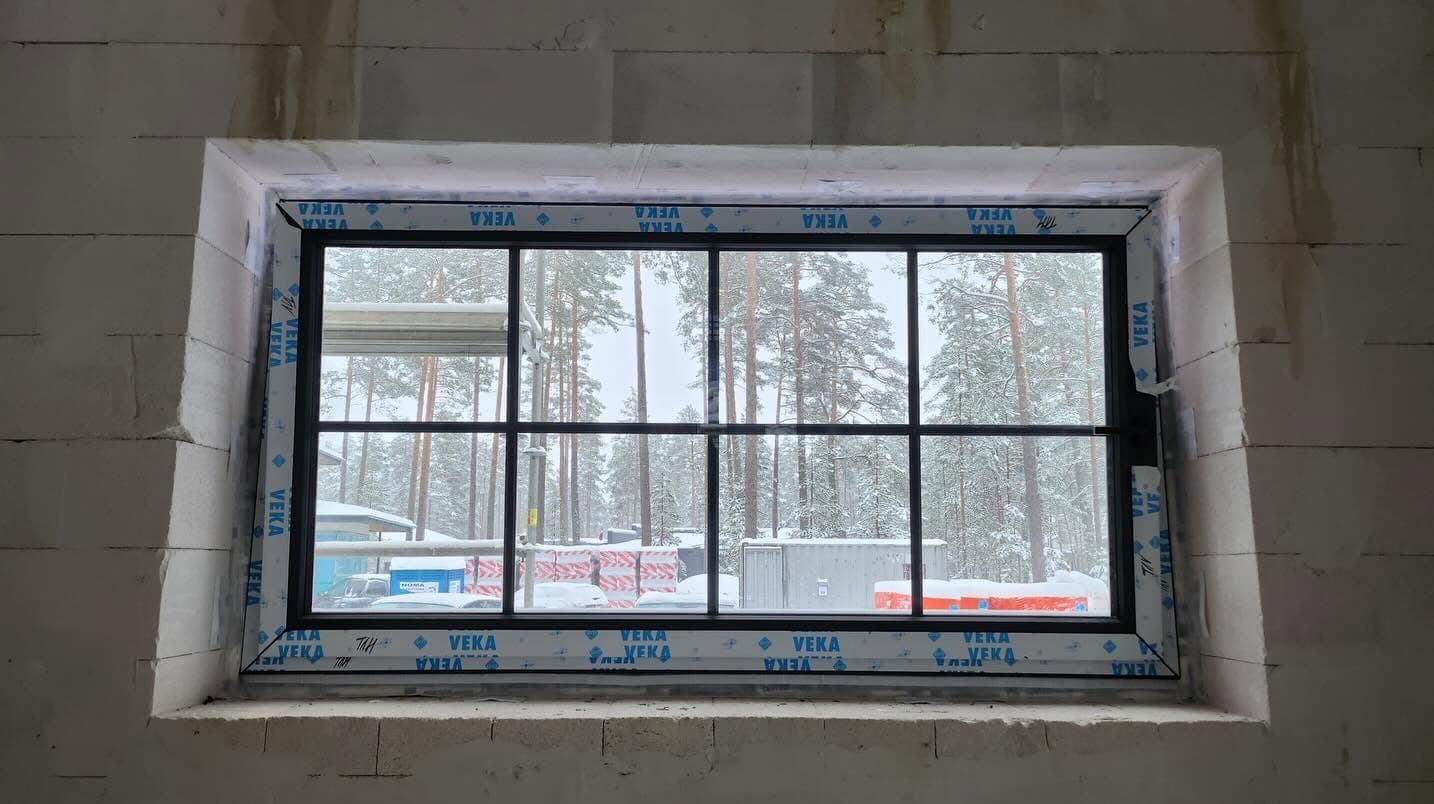 Rūtots logs ar tumšu rāmi, uzstādīts gāzbetona sienā